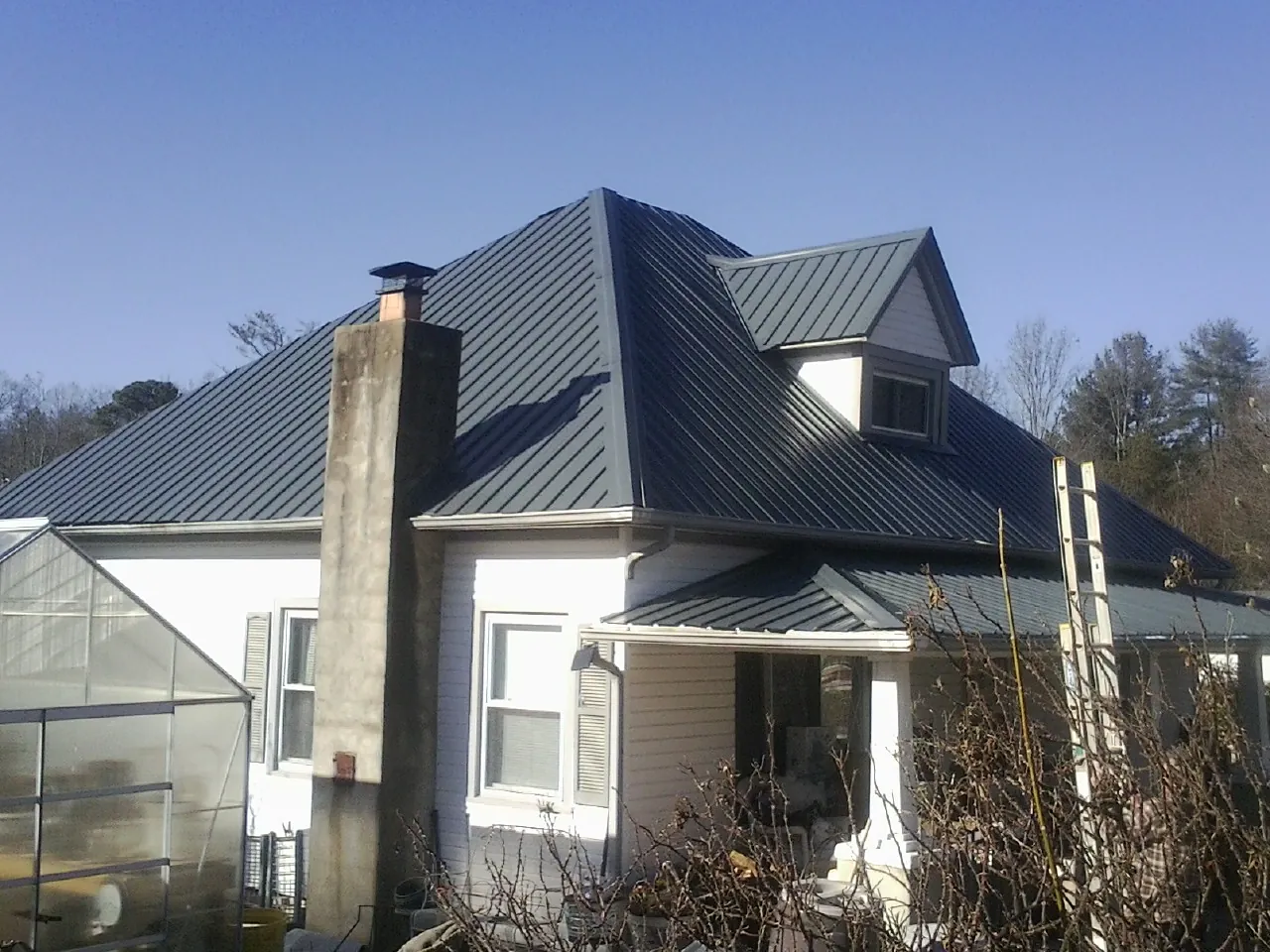 Dark blue standing seam metal roof on a white farmhouse with dormer — Slate & Tile Roof Repair by Roofing Brothers in Whigham