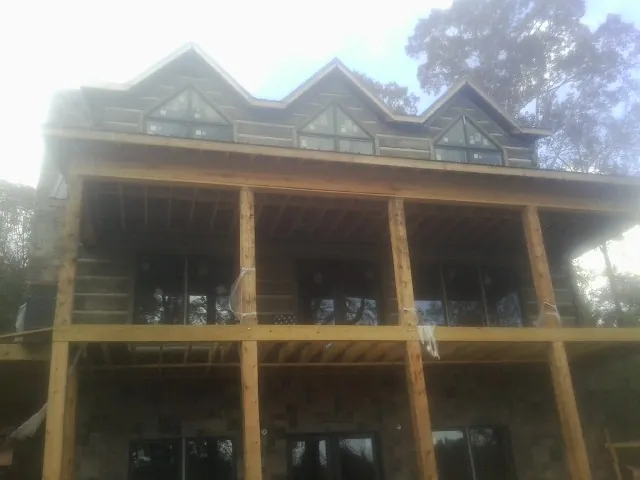 Dormers and porch framing on a large log home under construction — Roof Coating work by our crew in Whigham
