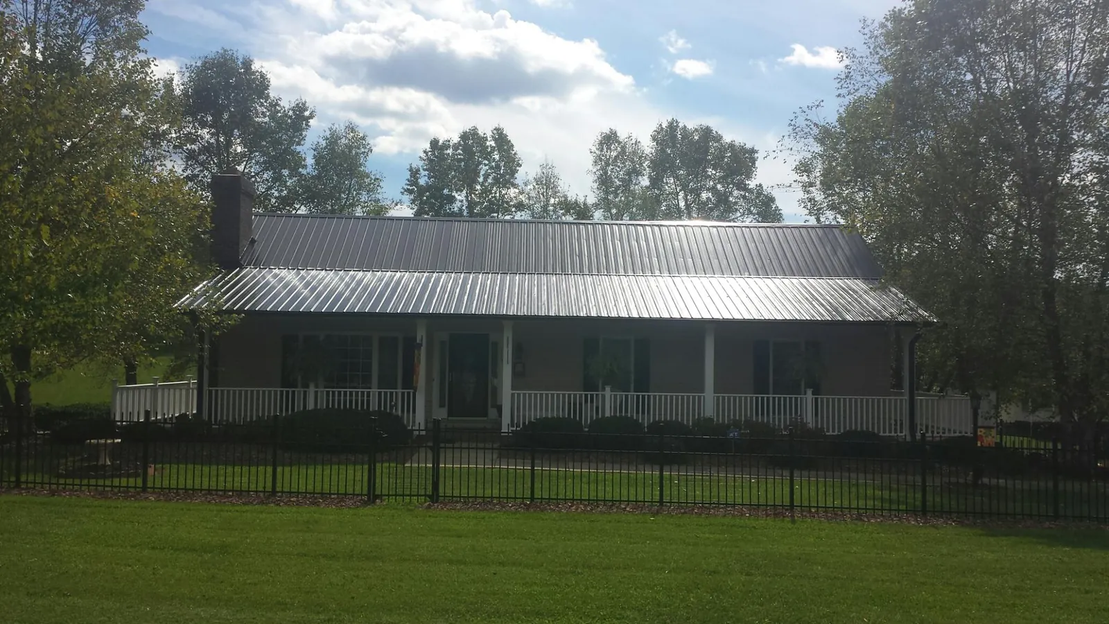 Gray metal roof on a brick ranch with a full width front porch — Gutter Guard Installation work by our crew in Whigham