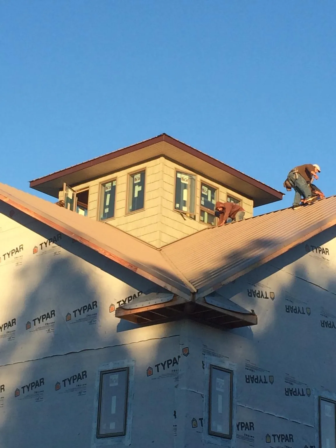 Roofers working around a rooftop cupola on a new metal roof at sunset — Roof Waterproofing in Whigham by Roofing Brothers